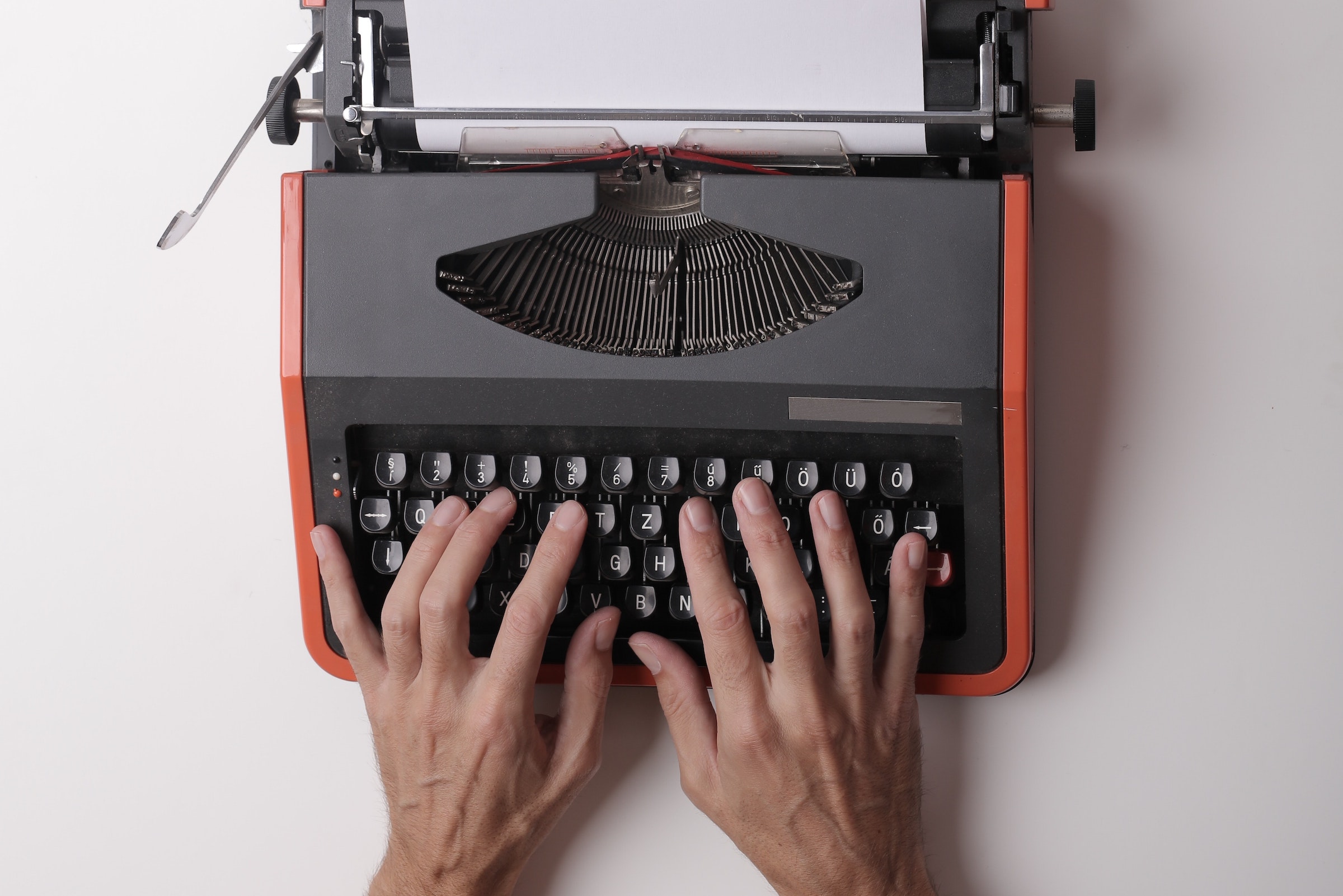 contenu d'un e-mail - mains sur une machine à écrire rouge - Photo par Andrea Piacquadio - Pexels