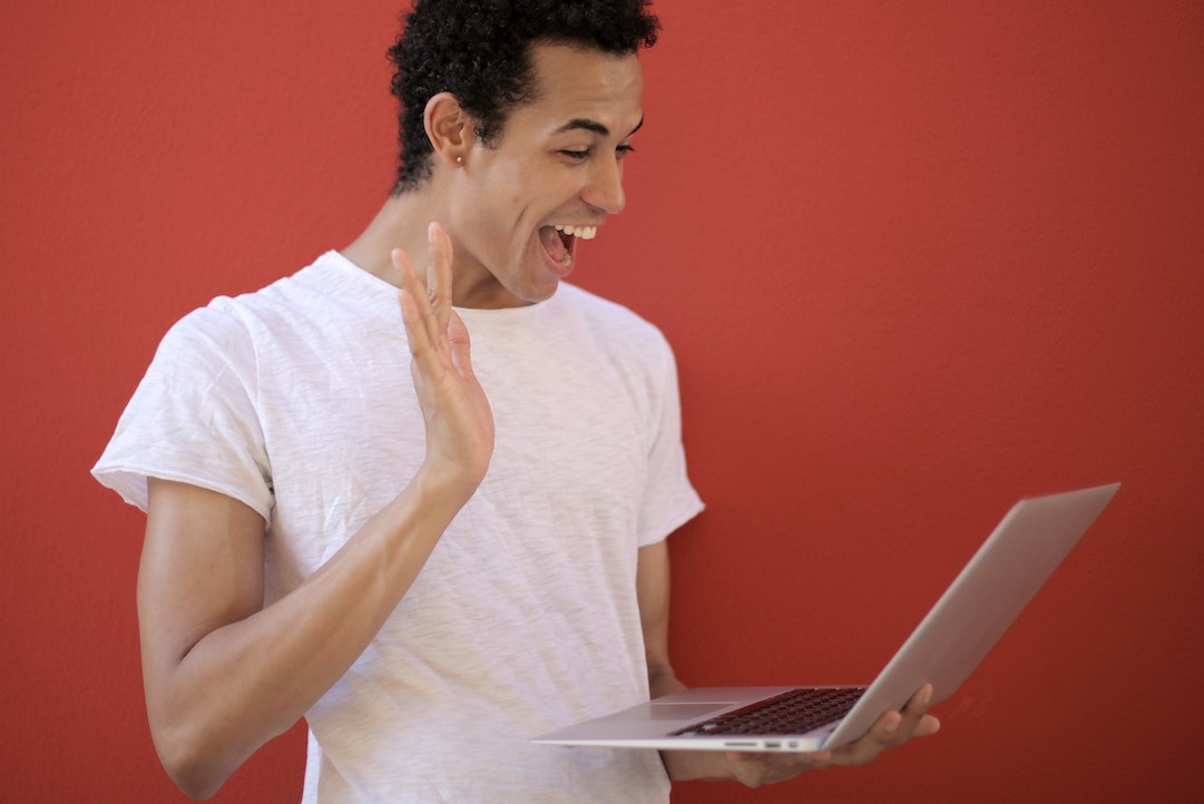 Homme souriant devant un ordinateur heureux de voir son email personnalisé - Photo par Andrea Piacquadio - Pixels